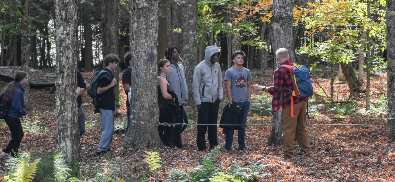 Elementary students gathered around a teacher working in a flower garden