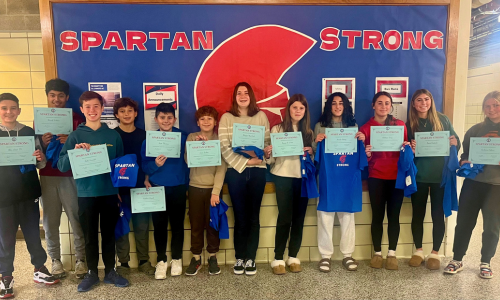 a group of students holding certificates lined up in front of a bulletin board that says "Spartan Strong"